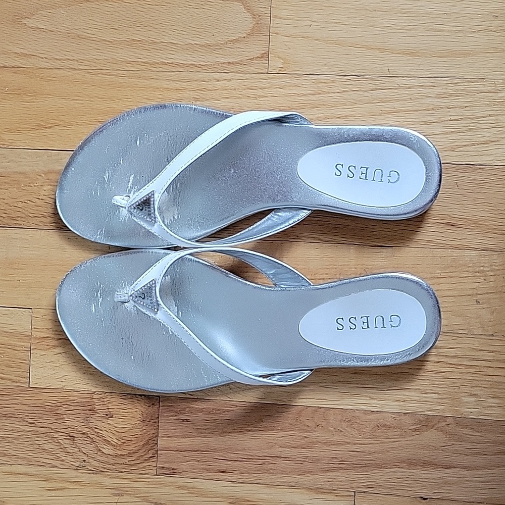 White flip flop sandal by Guess, size 9 w/ silver guess emblem.